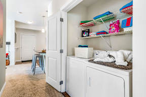 Laundry room with washer dryer and storage shelves at Mullan Reserve Apartments, Missoula