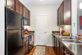 Galley kitchen with stainless steel appliances and dark wood cabinets at Mullan Reserve Apartments, Missoula