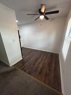 A ceiling fan is mounted on a wall in a room with a wooden staircase.
