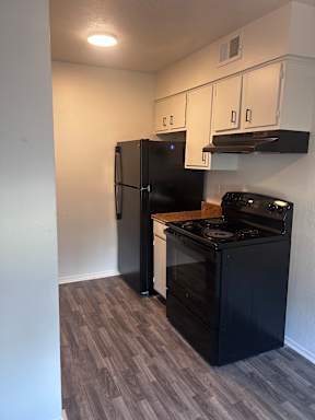 A black microwave is installed above a black oven.