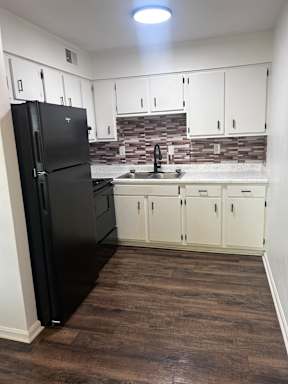 A black piano in a room with white drawers and a brown wall.