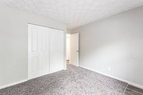 a bedroom with a white door and carpeted floor