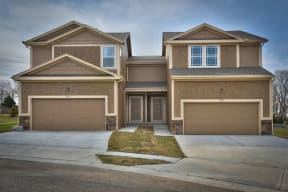 a brown house with two garage doors