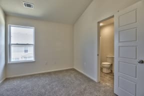 an empty bedroom with a toilet and a door to the bathroom