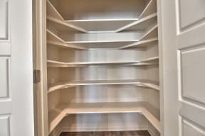 a walk in closet with white shelves and a door