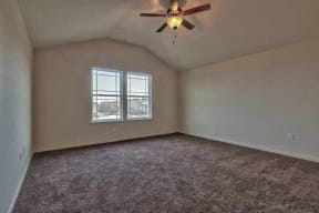 an empty living room with a ceiling fan and a window