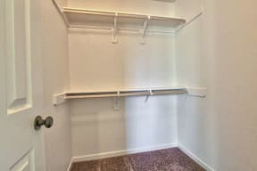 a walk in closet with a white wall and a hanging rail