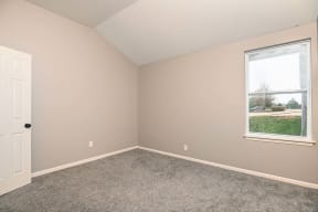 an empty bedroom with a window and carpet