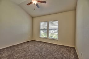 an empty living room with a ceiling fan and a window