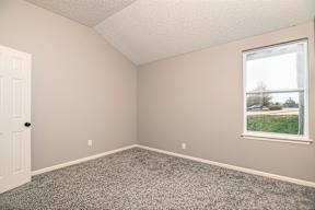 A room with a carpeted floor, a window, and a door.