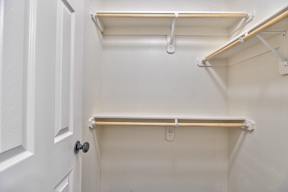 A white door is open to a pantry with two shelves.