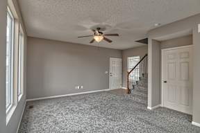 A room with a ceiling fan and carpeted floor.