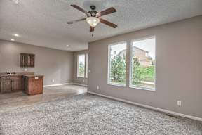 A room with a ceiling fan and carpeted floor.