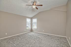 A room with a ceiling fan and carpeted floor.