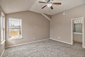 A room with a ceiling fan and a window overlooking a building.