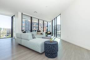 A modern living room with a white sofa and a round ottoman.