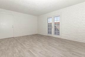 A room with a white door and a window with white blinds.