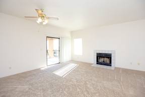 A living room with a fireplace and a ceiling fan.
