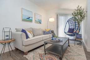 A living room with a white couch, a coffee table, and a hanging chair.