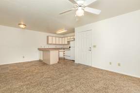A room with a ceiling fan and a kitchenette.