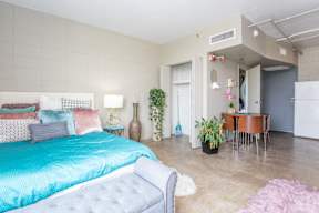 A bedroom with a blue bedspread and a white bed.