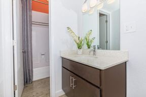 A bathroom with a brown vanity and a mirror above it.