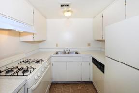 A kitchen with a white stove and white cabinets.