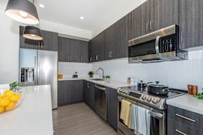 A modern kitchen with a stainless steel refrigerator, oven, and microwave.