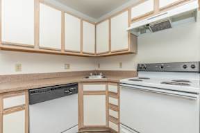 A kitchen with a white stove and wooden cabinets.