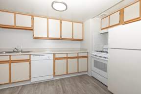 A kitchen with white appliances and wooden cabinets.