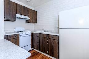 A kitchen with white appliances and wooden cabinets.