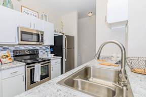 A kitchen with a stainless steel sink and white cabinets.