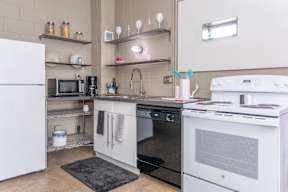 A kitchen with white appliances and a black rug on the floor.