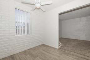 A room with a white ceiling fan and a window with blinds.