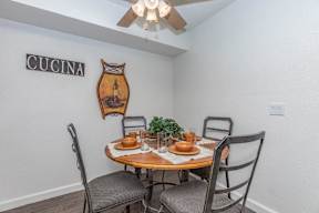 A dining room with a table set for two and a sign that says "CUCINA" on the wall.