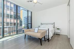 A bedroom with a large bed and a balcony overlooking a city.