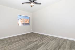 A room with a ceiling fan and a window with blinds.