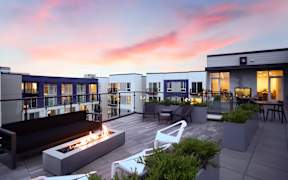 A modern outdoor seating area with a fire pit and chairs.