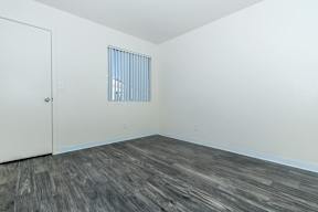 A room with a wooden floor and a window with blinds.