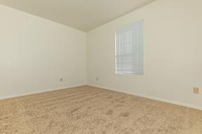 A room with a carpeted floor and a window with blinds.