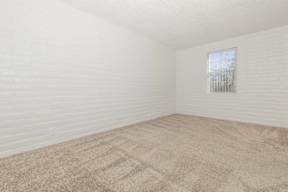 A room with a window and carpeted floor.