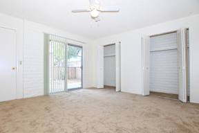 A room with a ceiling fan and carpeted floor.