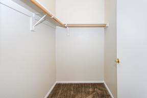A white door with a gold handle is on the right side of a room with a white wall and a brown carpet.