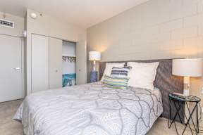 A bedroom with a bed, two lamps, and a nightstand.