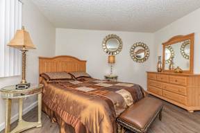 A bedroom with a bed, dresser, and mirror.