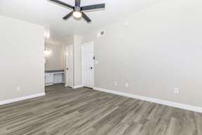 A room with a ceiling fan and wooden flooring.