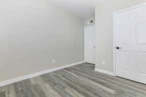 A room with a white door and a wooden floor.
