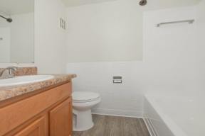 A white toilet sits in a bathroom next to a sink and a bathtub.