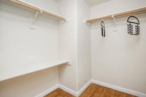 A white closet with two shelves and two hangers.