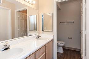 A bathroom with a white counter top and a white toilet.